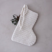 White crocheted Christmas stocking on a grey background