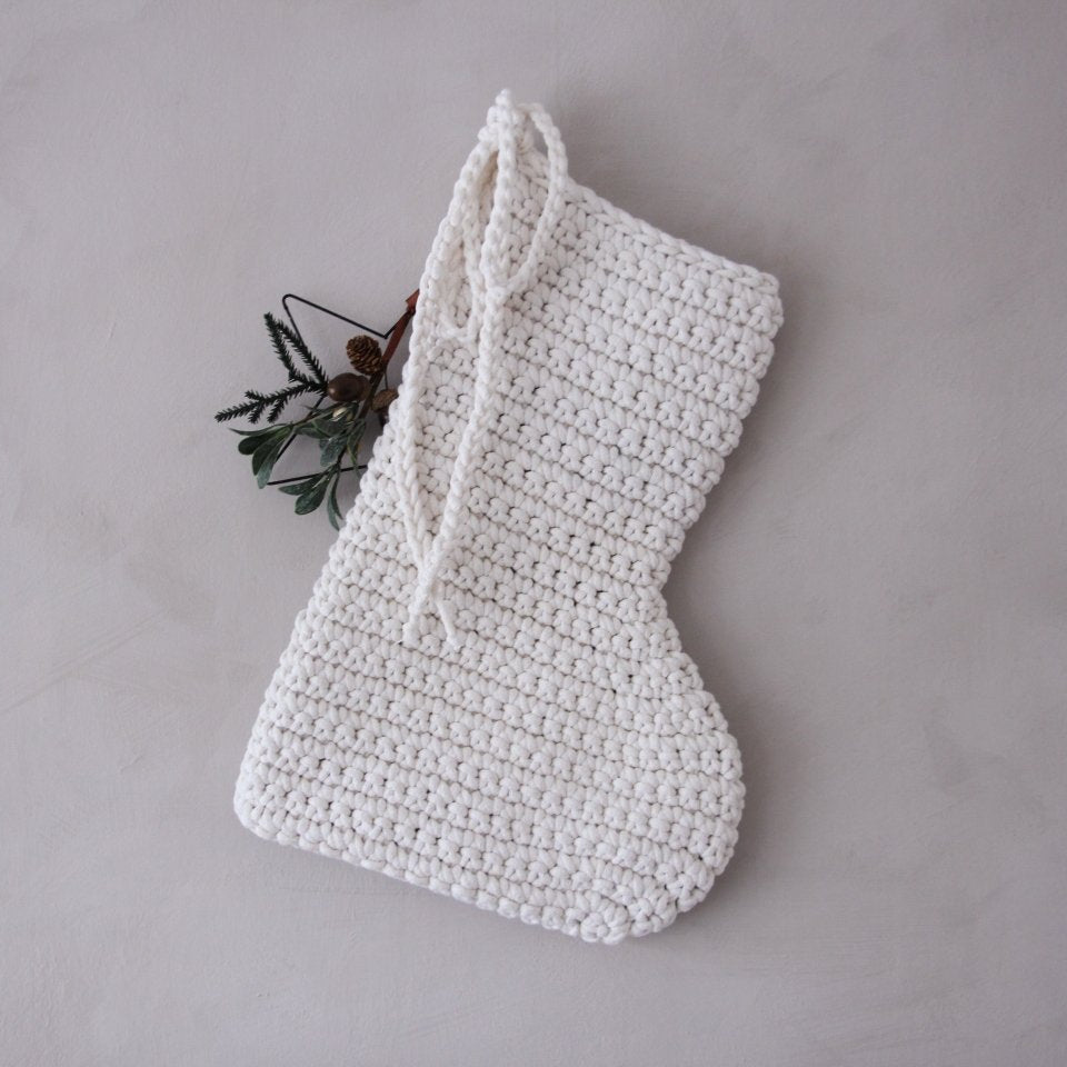 White crocheted Christmas stocking on a grey background