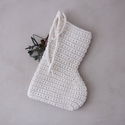 White crocheted Christmas stocking on a grey background