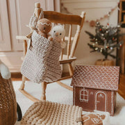 Children's room with wooden rocking chair, knitted Christmas stocking, and small gingerbread house.