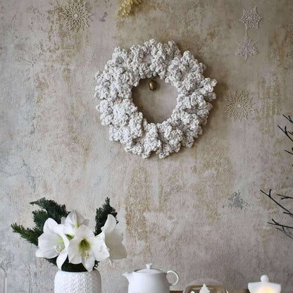 Decorative setting with a wreath, candles, and teapots on a textured wall background