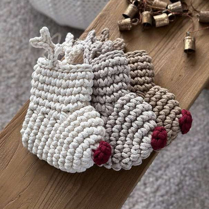 Crocheted Christmas stockings with antlers and red noses on a wooden surface