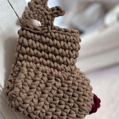 Brown knitted reindeer Christmas stocking with a red nose on a white surface