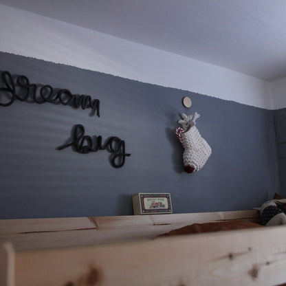 Kids bedroom with a wooden shelf, decorative items, and a hanging lamp.
