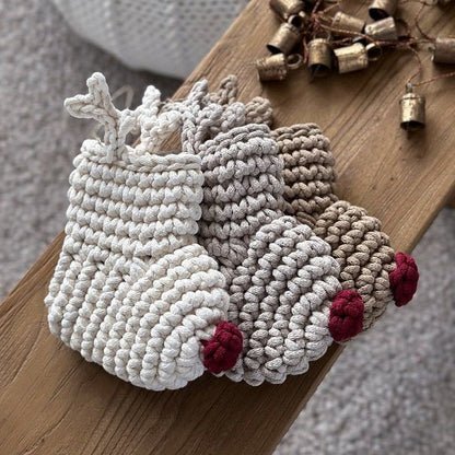 Crocheted reindeer Christmas stocking ornaments with red noses on a wooden surface