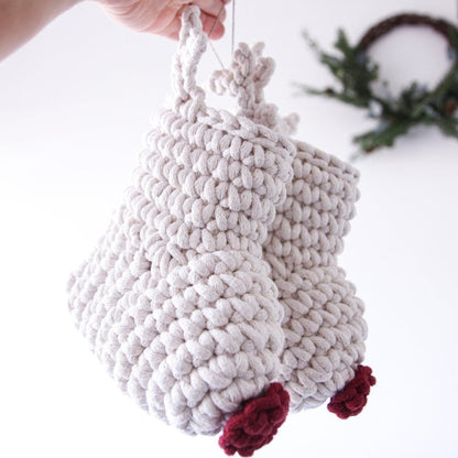 Handmade crochet reindeer Christmas stockings with red noses held by a hand against a white background
