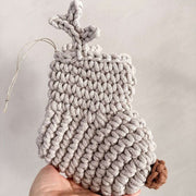 Handmade crocheted Christmas stocking with antlers and a brown nose held by a hand against a neutral background