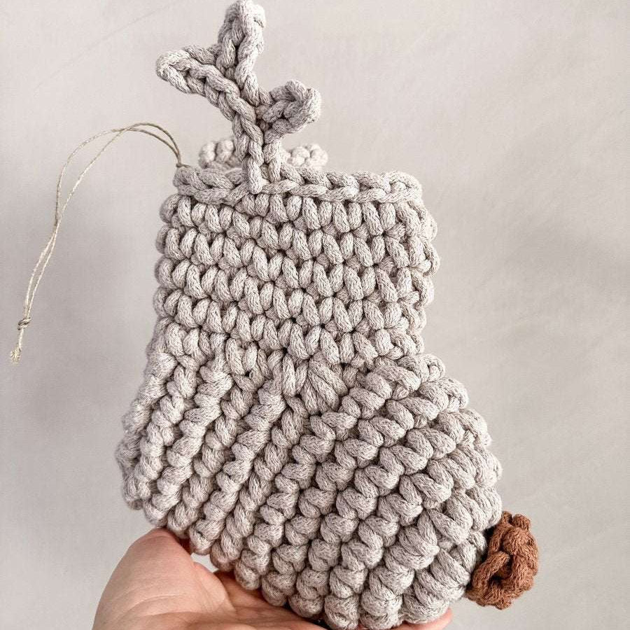 Handmade crocheted Christmas stocking with antlers and a brown nose held by a hand against a neutral background
