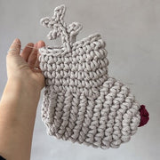 Hand holding a crocheted reindeer Christmas stocking with a red nose and antlers against a plain background