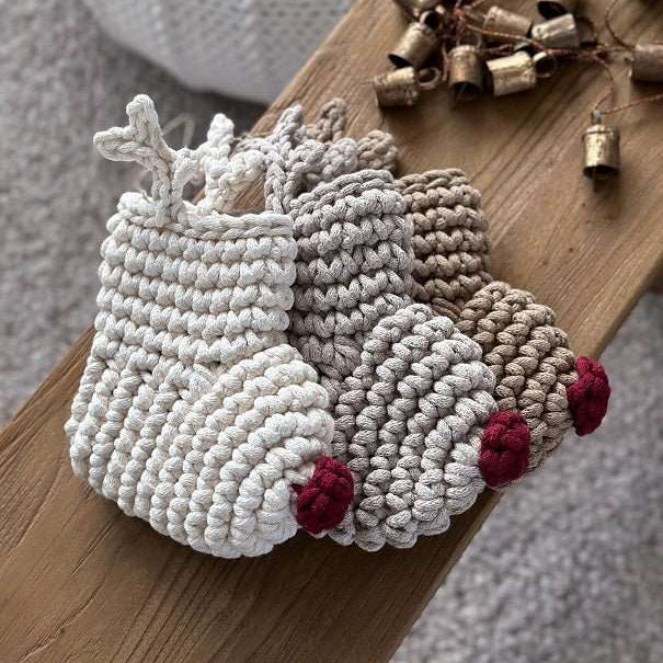 Three crocheted reindeer Christmas stockings on a wooden board