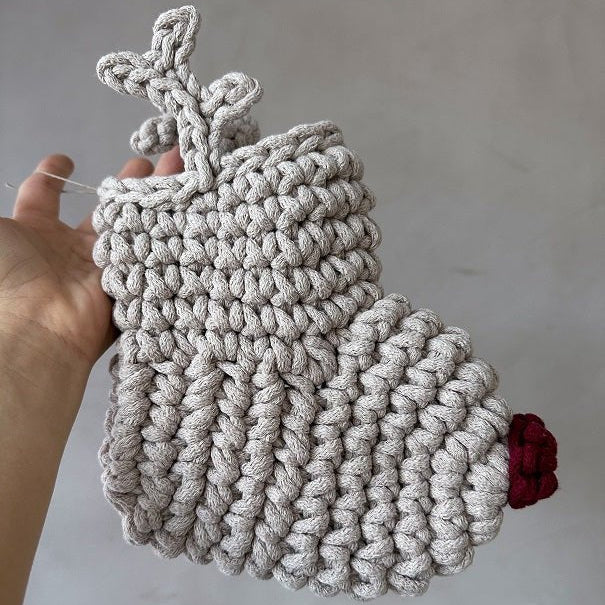Handmade crocheted reindeer Christmas stocking with antlers and a red nose held against a plain background