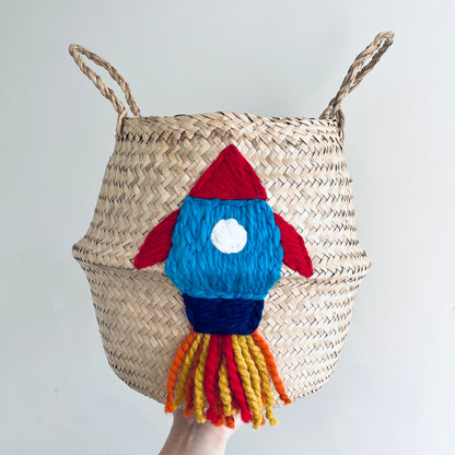 Woven basket with a colourful rocket-shaped decoration on a plain background