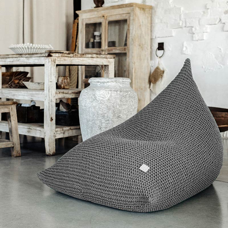 Grey bean bag chair in a room with white walls and wooden furniture.
