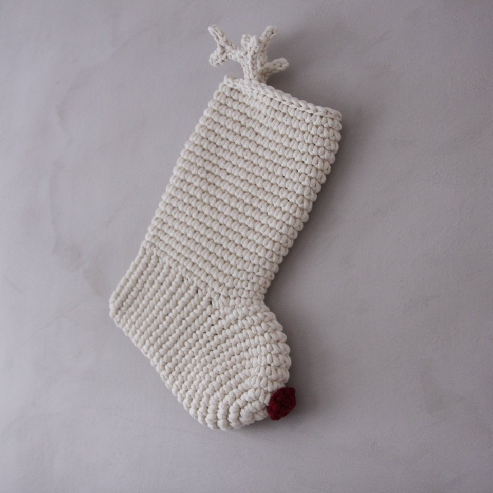 Knitted Christmas stocking with a red nose and antlers on a grey background