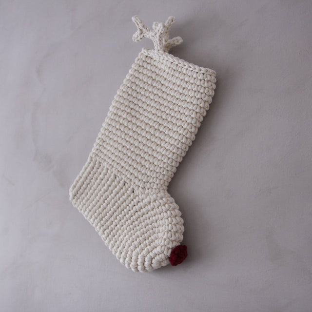 Knitted Christmas stocking with a red nose and antlers on a grey background