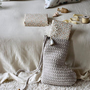 Crocheted Chrisrtmas stocking with decorative items on a textured surface