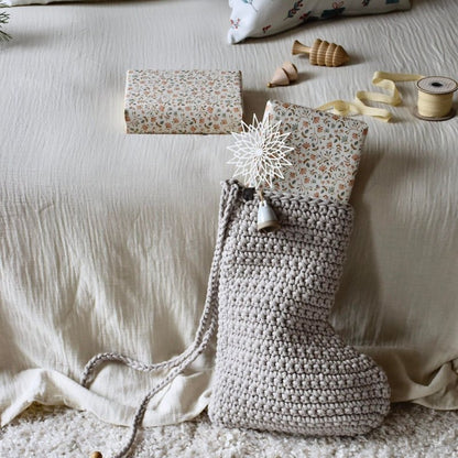 Crocheted Chrisrtmas stocking with decorative items on a textured surface