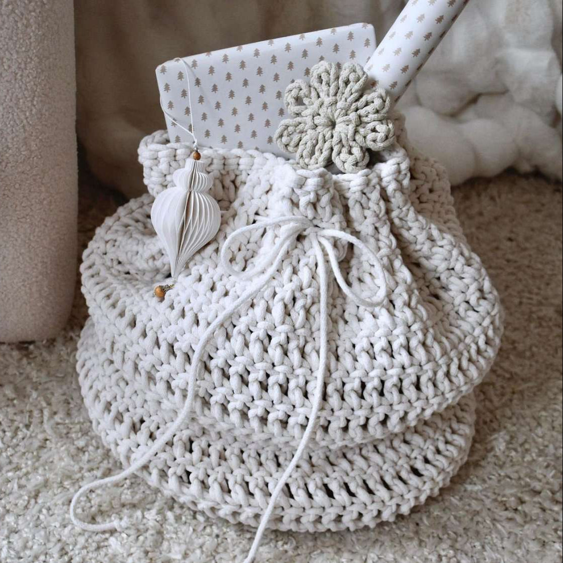 Crocheted present bag with decorative elements on a soft surface
