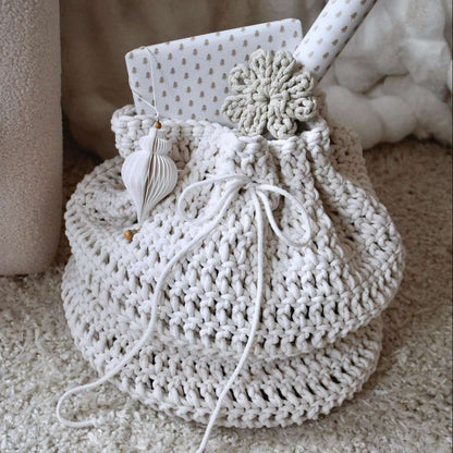 Crocheted present bag with decorative elements on a soft surface