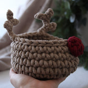 Handmade crochet basket with deer antlers and a red nose held in a hand.
