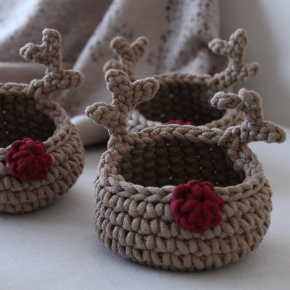 Three crocheted reindeer-shaped baskets with red noses on a light background