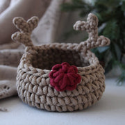Crocheted reindeer basket with antlers and a red nose on a neutral background