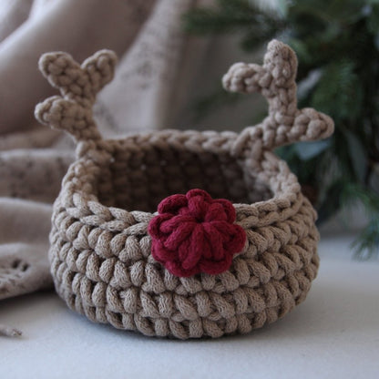 Crocheted reindeer basket with antlers and a red nose on a neutral background