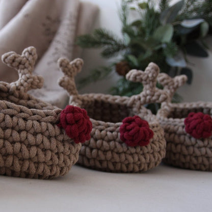 Three crocheted reindeer baskets with red noses on a neutral background