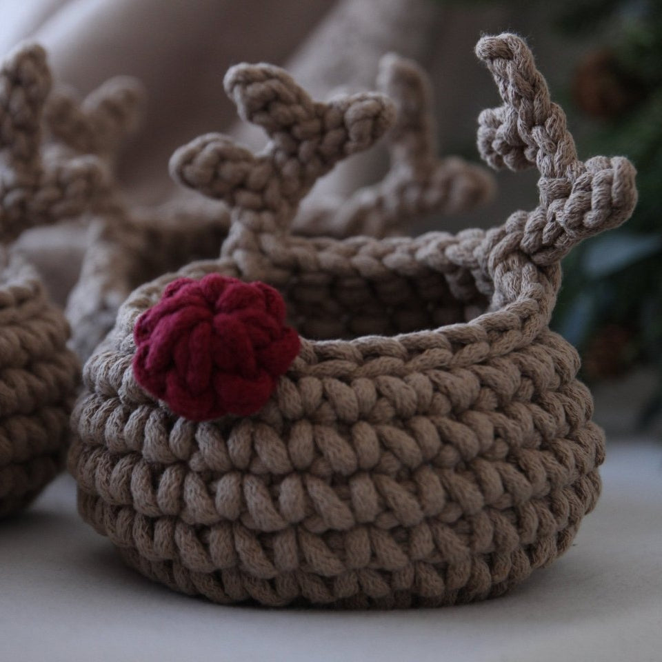 Knitted reindeer basket with red nose on a neutral background