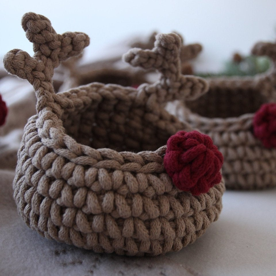 Two crocheted reindeer-shaped baskets with red noses on a light background.