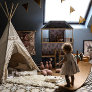 Child playing in a playroom with a teepee, dollhouse, and colorful flags.