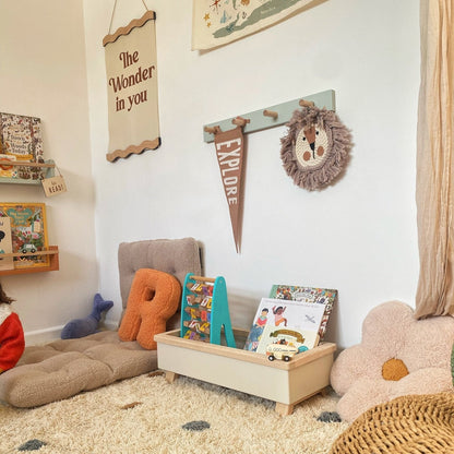 Children's playroom with toys, books, and decorative elements on a carpeted floor.