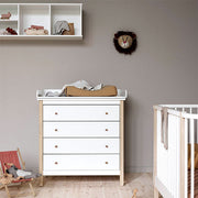 Modern white and oak wood nursery dresser with four soft-close drawers and removable changing top in a contemporary baby room setting.