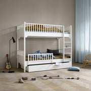 White Oliver Furniture Seaside Classic solid wood bunk bed with built-in storage ladder and trundle drawer, featuring Nordic design in a modern children's bedroom.
