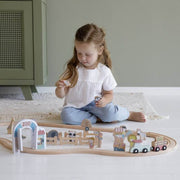 Young child playing with Little Dutch wooden zoo train set featuring animals, ticket booth, ice cream stand, and maintenance wagon on curved wooden track.