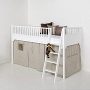 Oliver Furniture Seaside Classic Bed Curtain, shown in a white-framed loft bed with beige curtains, a ladder, and decorative pillows, creating a cozy and imaginative play space. 