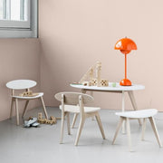 Oliver Furniture PingPong kids table in white and oak, accompanied by matching chairs and a bright orange lamp, perfect for a modern nursery or playroom. 