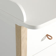 Modern white and natural oak wood nursery dresser with four soft-close drawers and removable changing table top, featuring curved contemporary design.