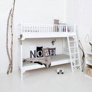White Oliver Furniture Seaside Classic solid wood bunk bed with Nordic design, vertical ladder, and storage railings in a minimalist children's bedroom.